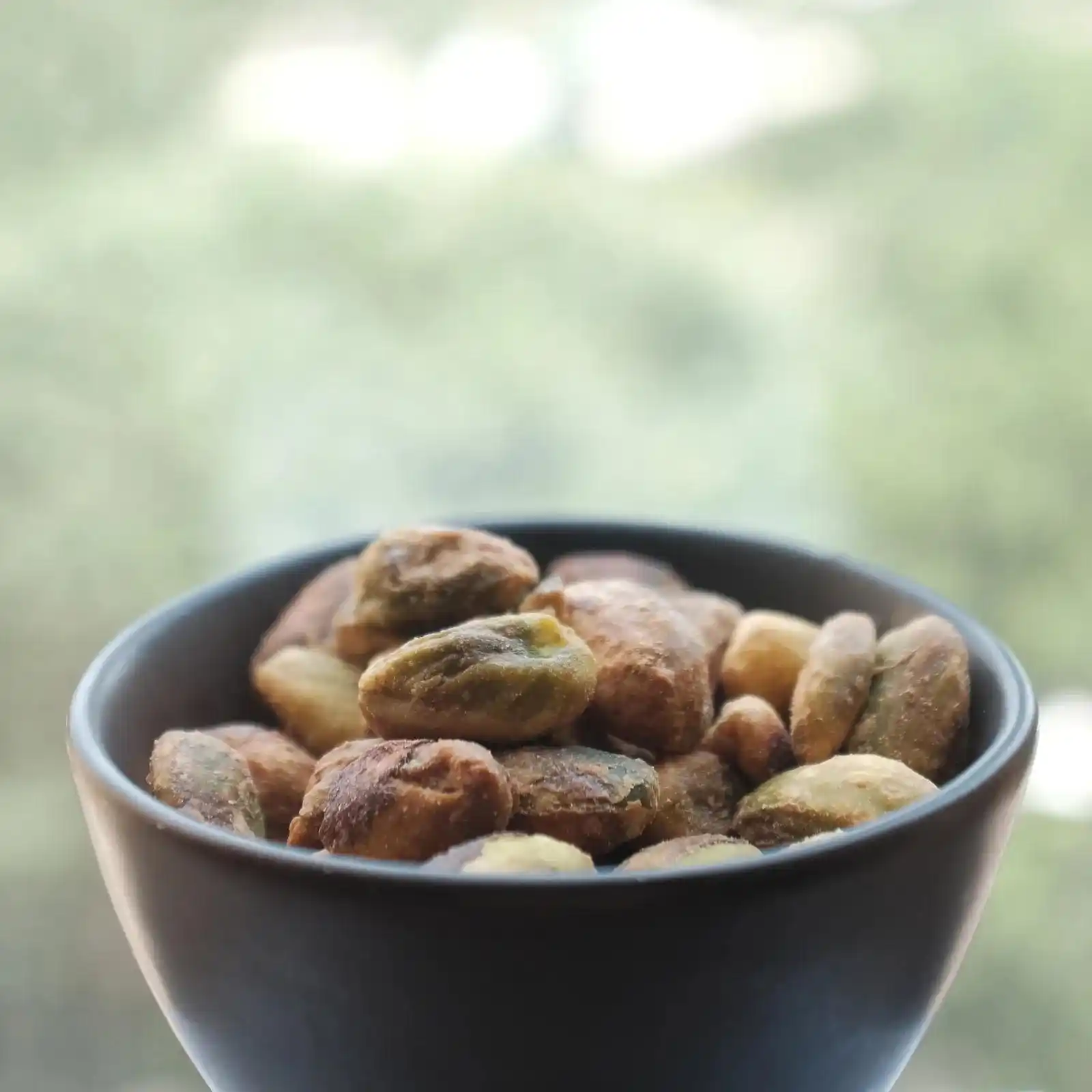 Shelled pistachios in a dark bowl